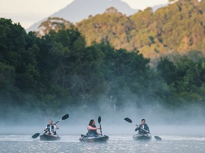 Friends enjoying an early morning kayak tour on Tweed River with scenic views of Mount Warning.